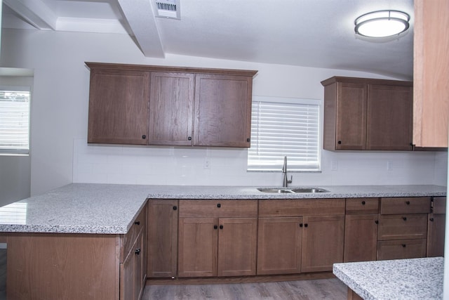 kitchen with tasteful backsplash, visible vents, wood finished floors, a peninsula, and a sink