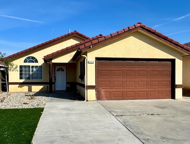 mediterranean / spanish house featuring an attached garage, driveway, and stucco siding