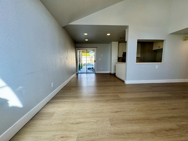 interior space with recessed lighting, vaulted ceiling, baseboards, and wood finished floors