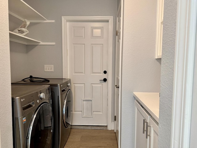 laundry room featuring washer and dryer, cabinet space, and wood finished floors