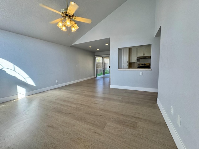 unfurnished living room with high vaulted ceiling, a ceiling fan, baseboards, and wood finished floors