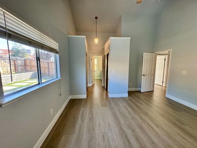 spare room with a high ceiling, wood finished floors, and baseboards