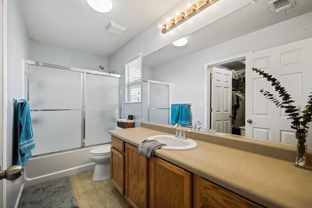 full bathroom featuring visible vents, bath / shower combo with glass door, toilet, tile patterned floors, and vanity