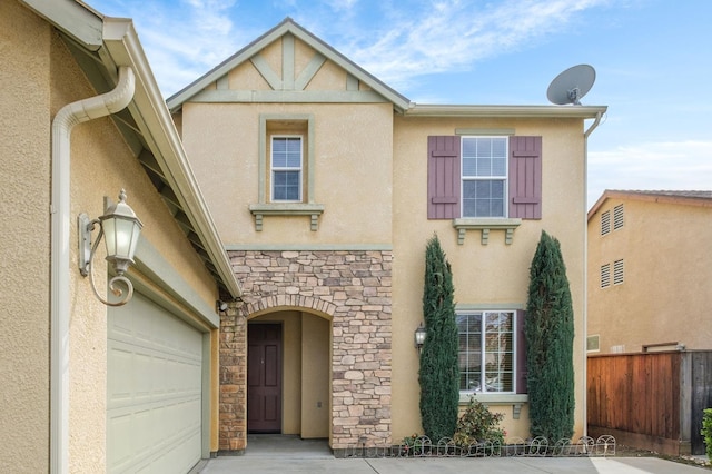 view of front of property with stone siding, fence, and stucco siding