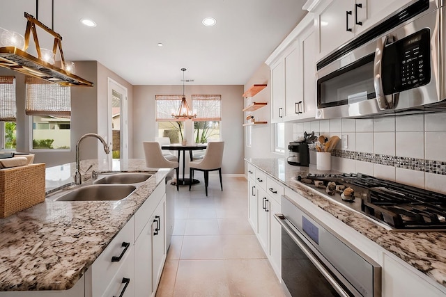 kitchen with light tile patterned floors, stainless steel appliances, a sink, tasteful backsplash, and pendant lighting