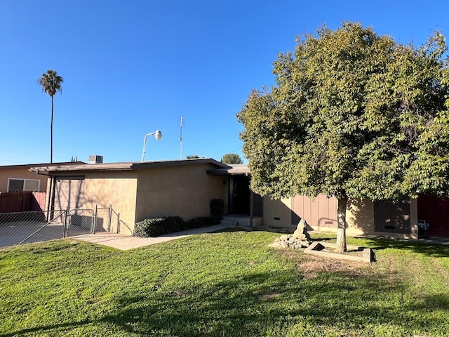 back of property with stucco siding, a gate, fence, and a yard