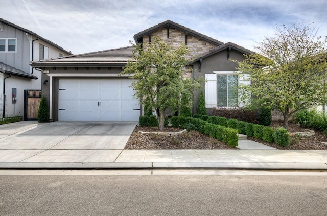 view of front of house featuring a tiled roof, concrete driveway, stucco siding, stone siding, and an attached garage