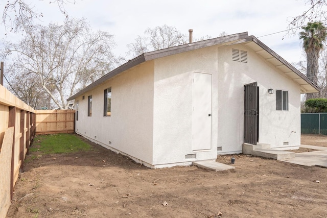 back of house featuring crawl space, a fenced backyard, and stucco siding