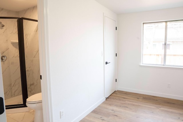 full bath with toilet, a marble finish shower, baseboards, and wood finished floors