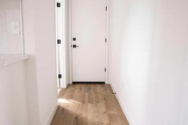 hallway featuring baseboards and light wood finished floors