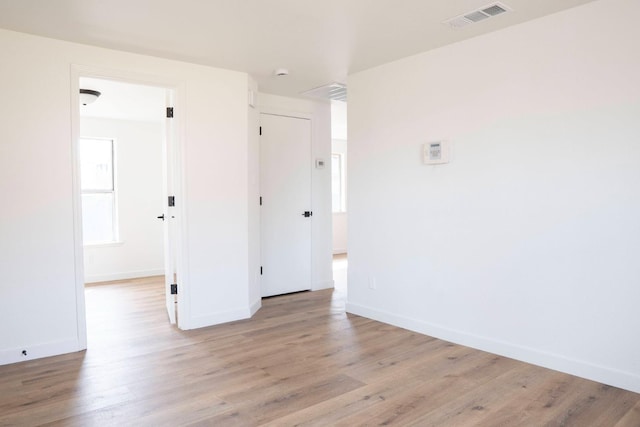 spare room featuring light wood-style floors, visible vents, and baseboards