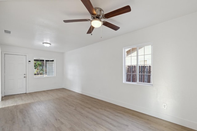 spare room featuring a ceiling fan, wood finished floors, visible vents, and baseboards