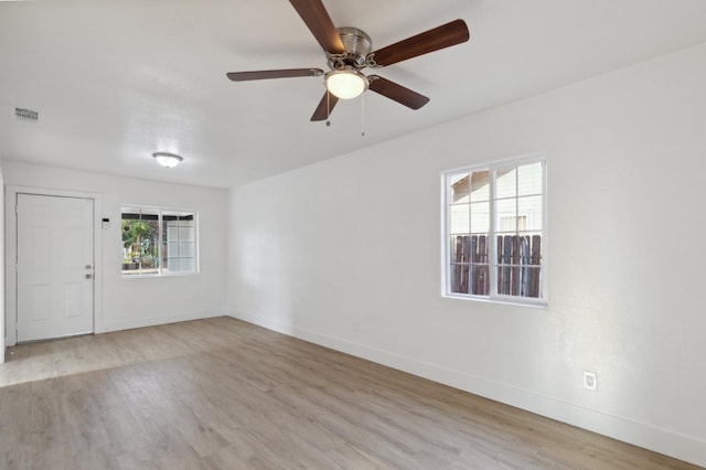 spare room featuring wood finished floors, visible vents, baseboards, and ceiling fan