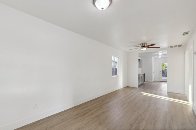 unfurnished living room featuring light wood-style floors, a wealth of natural light, and baseboards