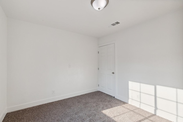 spare room featuring carpet floors, visible vents, and baseboards