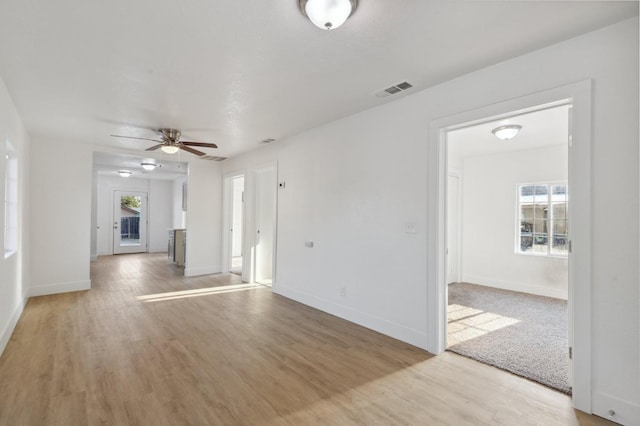 unfurnished living room with a ceiling fan, visible vents, baseboards, and wood finished floors