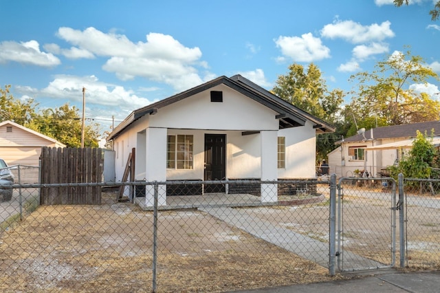 bungalow featuring a fenced front yard, a gate, and stucco siding