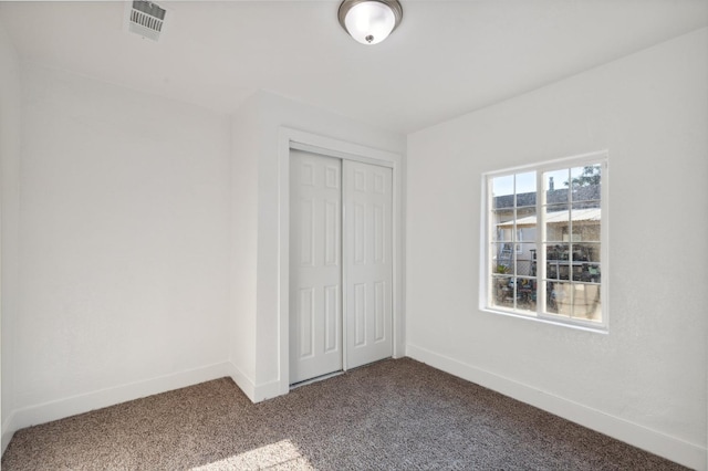 unfurnished bedroom with carpet, visible vents, baseboards, and a closet