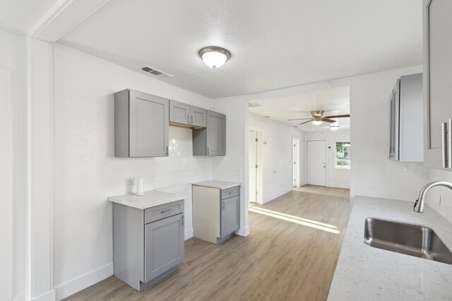 kitchen with light wood-type flooring, backsplash, a sink, and gray cabinetry