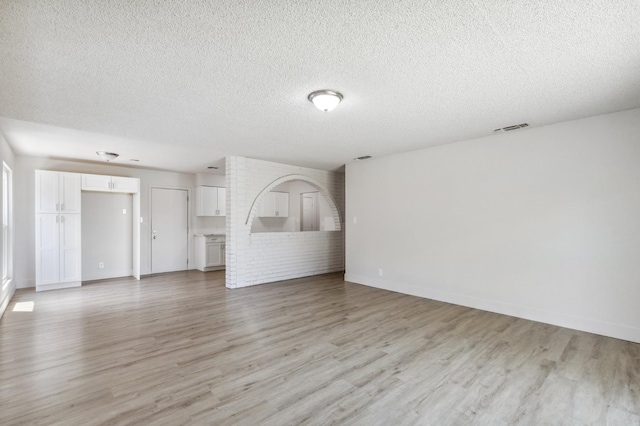 unfurnished living room featuring light wood-type flooring, visible vents, and a textured ceiling