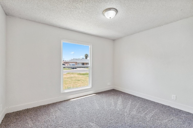 carpeted spare room with a textured ceiling and baseboards