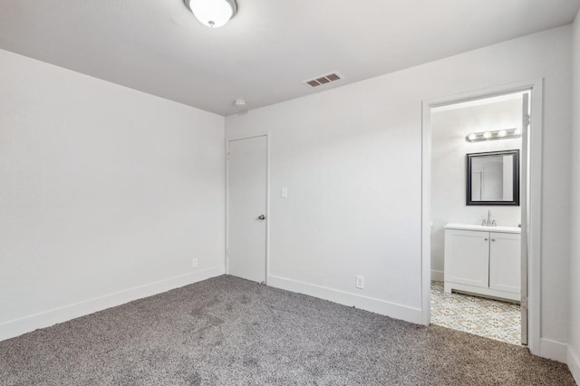 unfurnished bedroom with baseboards, visible vents, connected bathroom, and carpet flooring