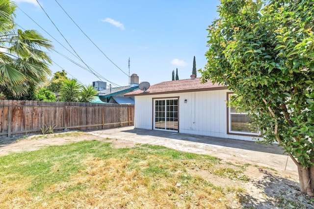 rear view of property featuring fence, a lawn, and a patio