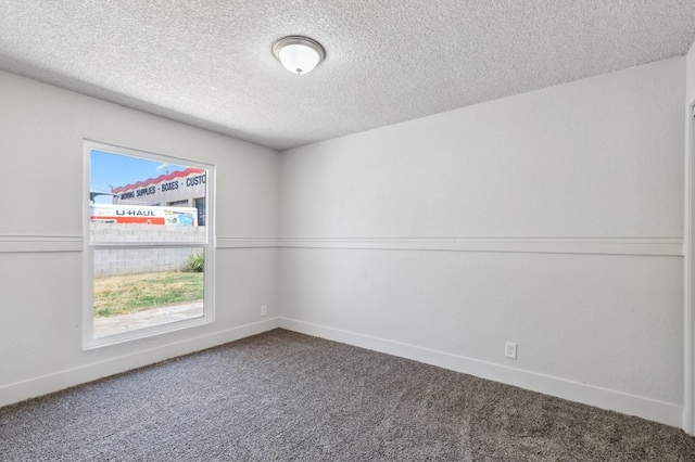 carpeted spare room with a textured ceiling and baseboards