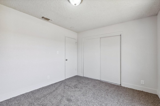 unfurnished bedroom featuring carpet floors, a closet, visible vents, and a textured ceiling