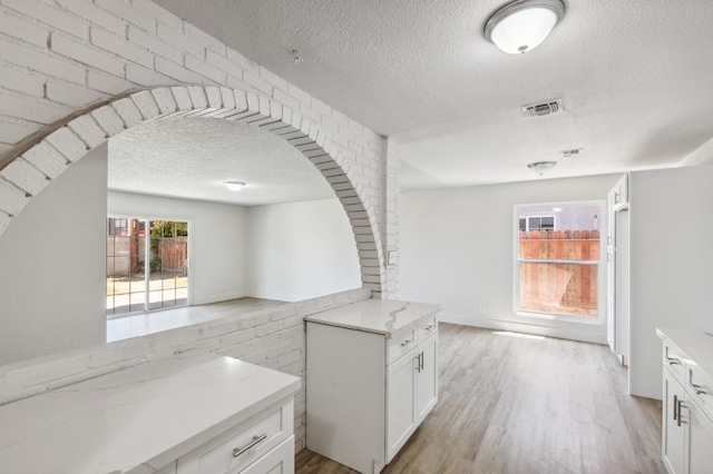 kitchen featuring light stone counters, open floor plan, visible vents, and light wood finished floors