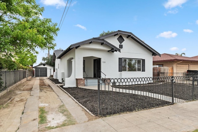 bungalow featuring a fenced front yard, concrete driveway, a detached garage, and stucco siding