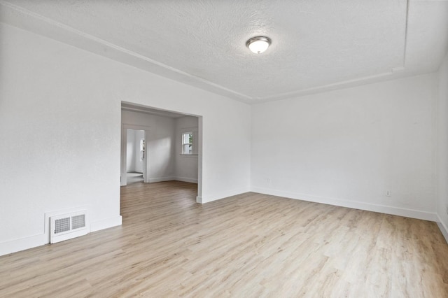 spare room featuring a textured ceiling, wood finished floors, visible vents, and baseboards