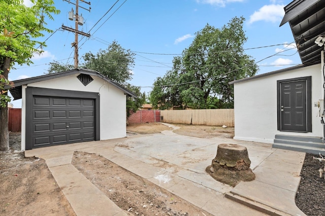 detached garage with concrete driveway and fence