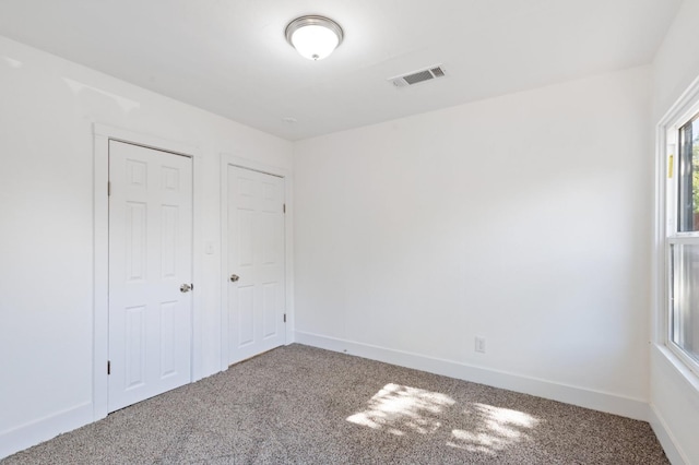 unfurnished room featuring carpet floors, baseboards, and visible vents