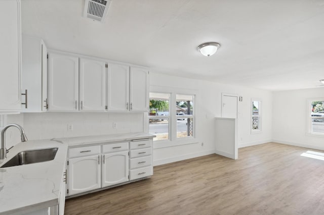 kitchen featuring plenty of natural light, visible vents, a sink, and light stone countertops