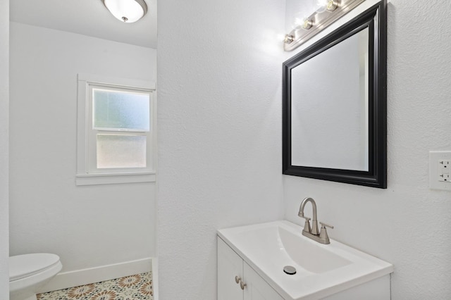 bathroom with toilet, vanity, and baseboards