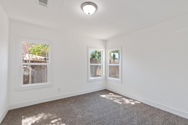 spare room featuring carpet floors, visible vents, and baseboards