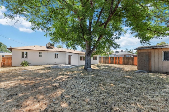 back of house featuring fence private yard, crawl space, an outdoor structure, and a storage shed