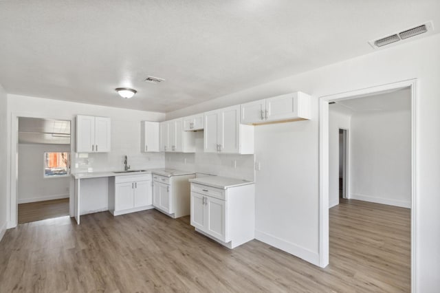 kitchen with light wood-style floors, visible vents, backsplash, and a sink