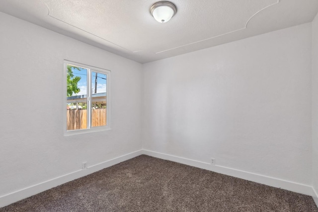 unfurnished room with dark carpet, a textured ceiling, and baseboards