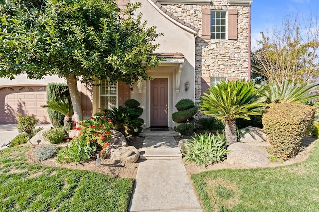 entrance to property with a garage, stone siding, driveway, and stucco siding