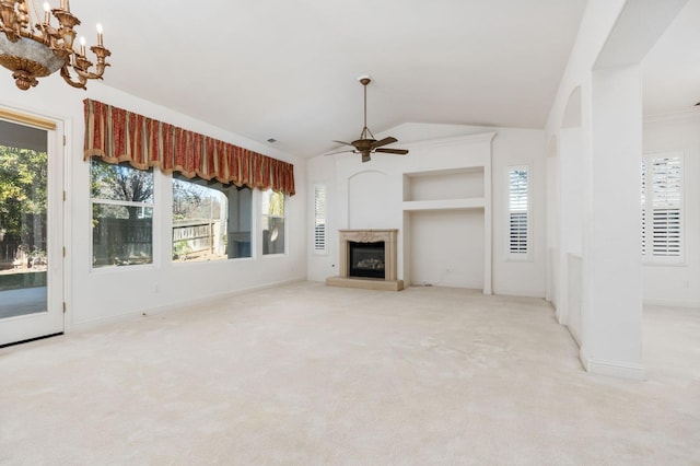 unfurnished living room with a wealth of natural light, a glass covered fireplace, vaulted ceiling, and carpet