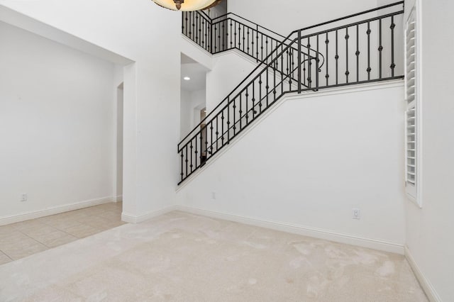 stairs with carpet floors, baseboards, and a high ceiling