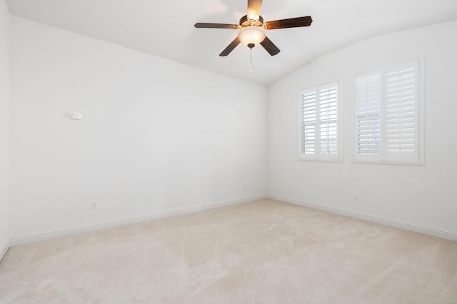 empty room featuring lofted ceiling, baseboards, a ceiling fan, and light colored carpet