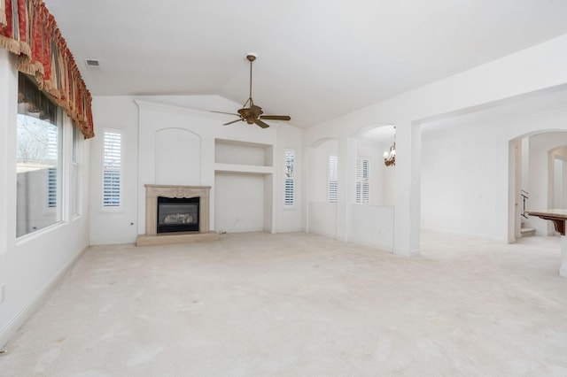 unfurnished living room featuring lofted ceiling, arched walkways, visible vents, a high end fireplace, and carpet