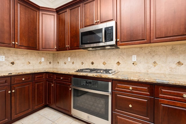 kitchen featuring light stone countertops, light tile patterned floors, stainless steel appliances, and decorative backsplash