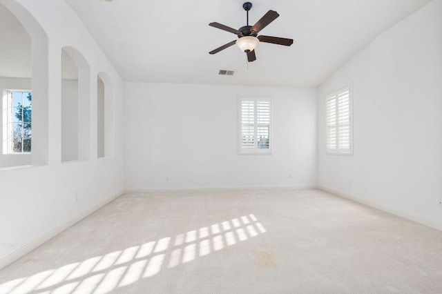 carpeted empty room featuring lofted ceiling, a ceiling fan, visible vents, and baseboards