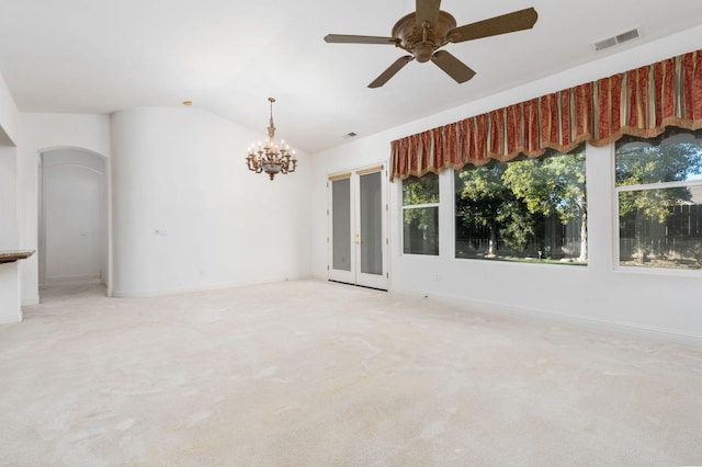 empty room with visible vents, arched walkways, light colored carpet, vaulted ceiling, and ceiling fan with notable chandelier