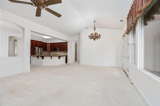 unfurnished living room featuring arched walkways, light colored carpet, ceiling fan with notable chandelier, visible vents, and vaulted ceiling