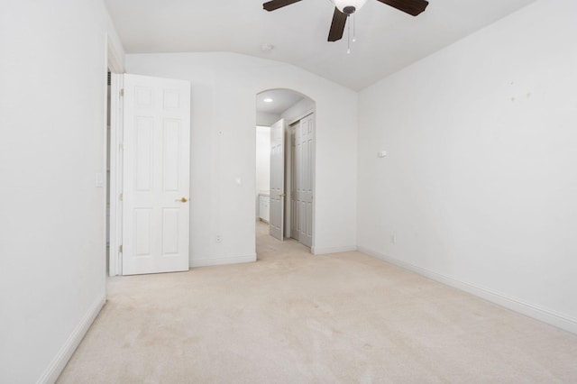 unfurnished bedroom with arched walkways, baseboards, lofted ceiling, carpet, and a closet